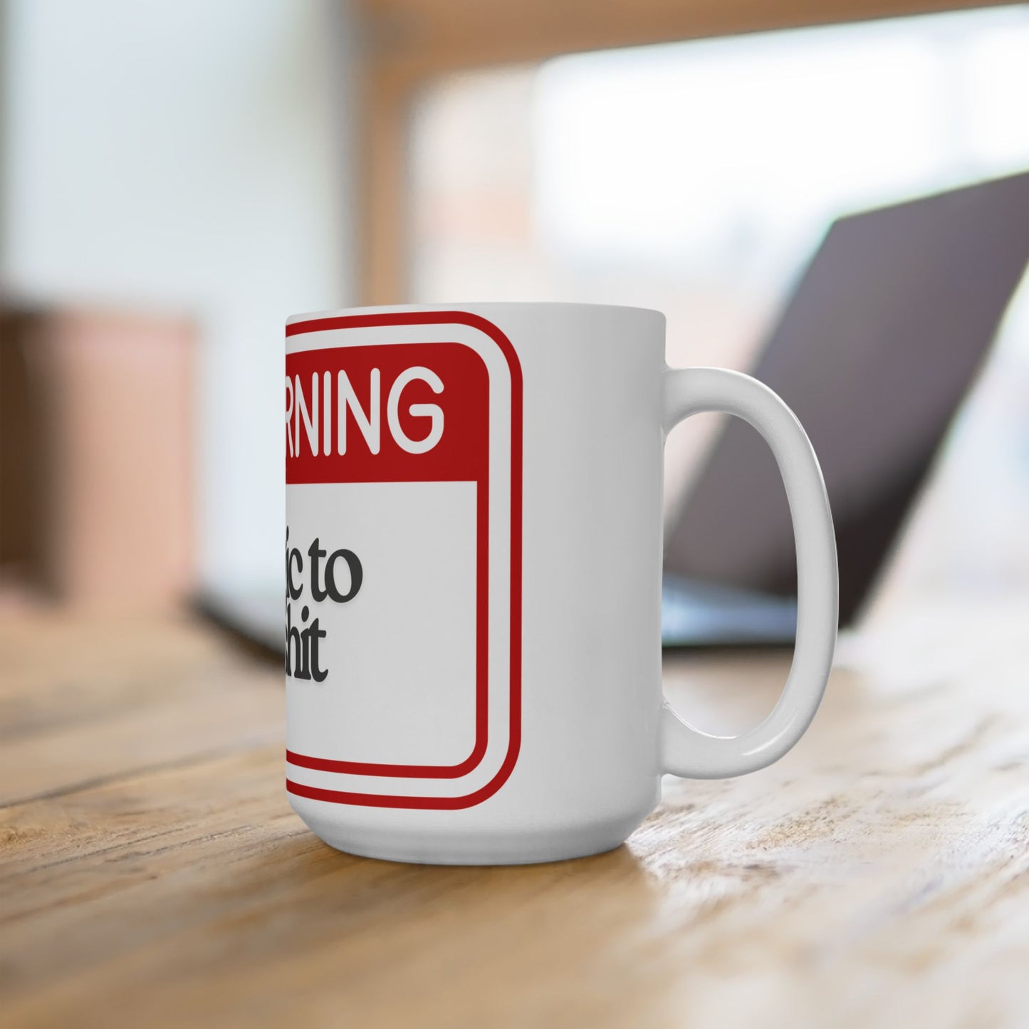 White mug with a red and black warning label design on a wooden surface.